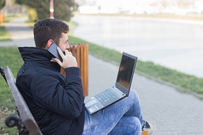 Midsection of man using mobile phone in water