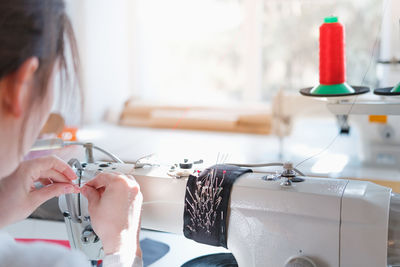 Close-up of woman using sewing machine in workshop