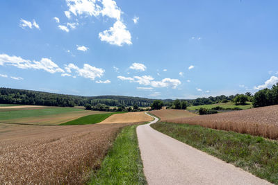 Road amidst field against sky