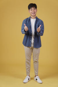 Portrait of smiling boy standing against yellow background