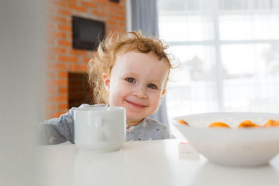 Smiling girl with a  cup of tea sitting at the table 