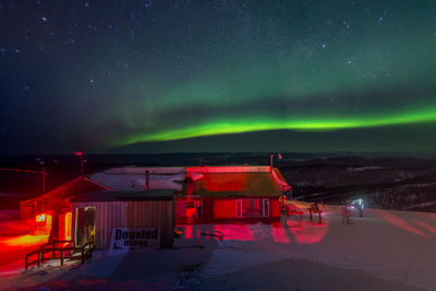 Illuminated buildings against sky at night during winter