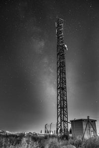 Low angle view of communications tower on field against sky