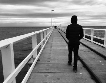 Rear view of man standing on jetty against sea