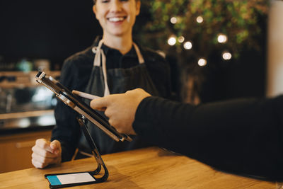 Cropped hand of male customer doing contactless payment through smart phone at coffee shop