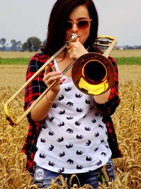 Woman playing trumpet while standing on field