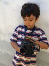 High angle view of boy with camera standing by wall