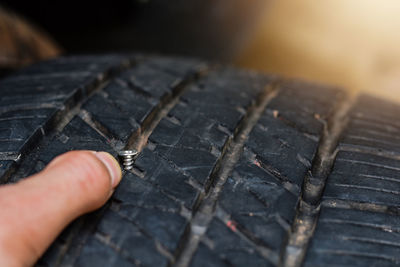 Close-up of hand touching screw in tire