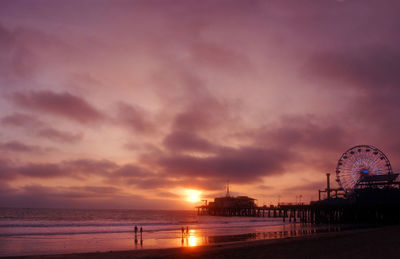 Santa monica pier at beach against sky during sunset