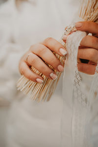 Burly large female fingers festive manicure with stones and sequins holding bride's dried flowers