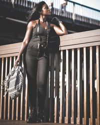 Low angle view of woman looking away while standing by railing