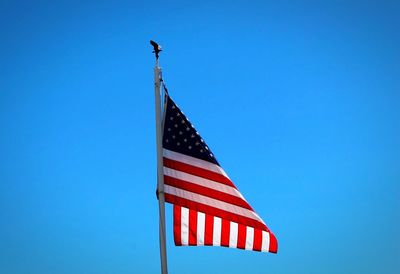 Low angle view of american flag against blue sky