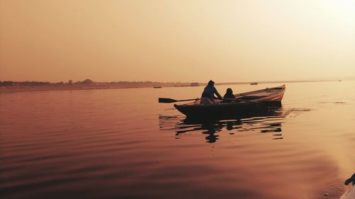 People in boat on sea against sky during sunset