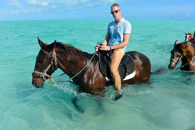 Full length of man riding horse in sea