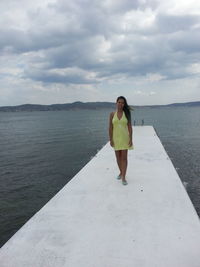 Portrait smiling young woman standing on pier over sea