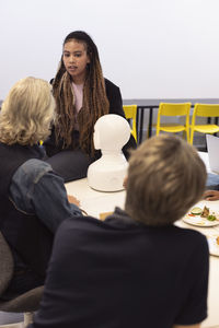 Business people discussing robot voice assistant during meeting