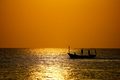 Silhouette boat in sea against orange sky