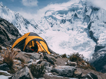 Tent by snowcapped mountains against sky