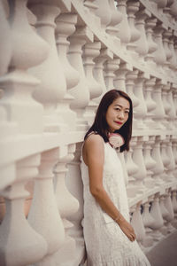 Portrait of young woman standing against wall