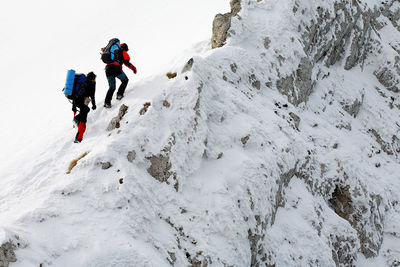 Low angle view of people walking on snowcapped mountain