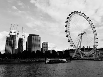 Ferris wheel in city against cloudy sky