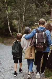 Rear view of family with backpack walking on footpath in forest
