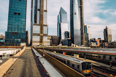 View of city street and modern buildings against sky