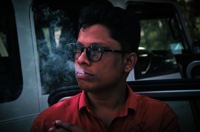 Portrait of young man smoking cigarette in car