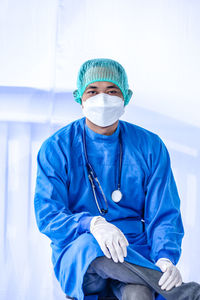 Portrait of doctor wearing mask against white background