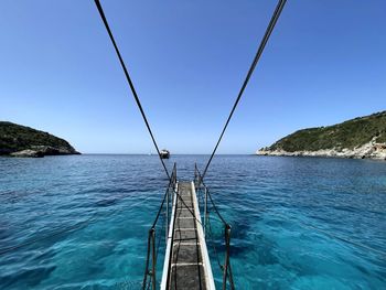 Sailboat on sea against clear blue sky