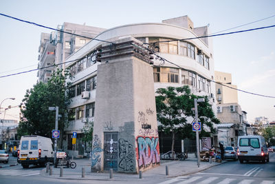 Cars on road by buildings against sky