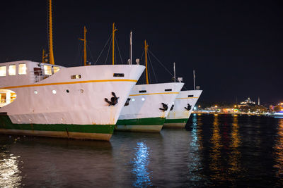 Sailboats moored in marina at night