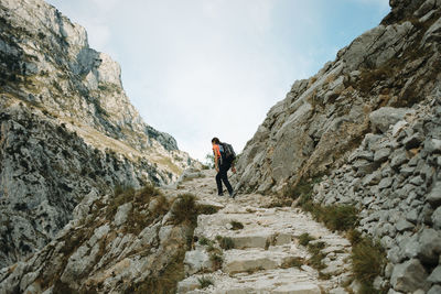 Rear view of man walking on rocks against mountains