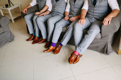 Low section of people sitting on tiled floor