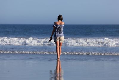 Rear view of woman standing on beach 