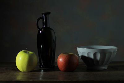 Still life composed of objects and fruit on wooden table and white cloth