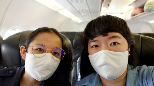 Two asian women travel with mask on during plane flight selfie