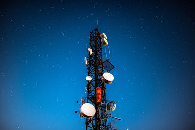 Low angle view of communications tower against sky at night