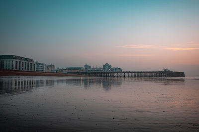 Scenic view of sea by buildings against sky during sunset