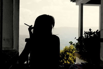 Silhouette of woman looking through window