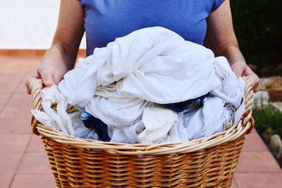 Midsection of woman holding laundry in basket at yard