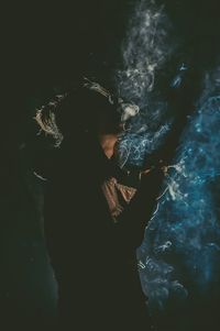 Man smoking cigarette against black background