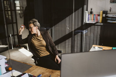 Female entrepreneur throwing paper while sitting at desk