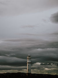 Lighthouse by sea against sky during sunset