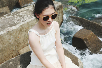 Portrait of young woman sitting on retaining wall