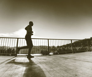 Man running quickly on shore bridge. silhouette of runner exercising and stretching on lake street