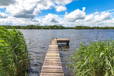 Wooden pier over lake against sky