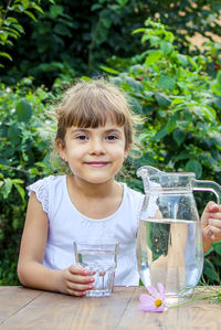 Portrait of young woman drinking water in park