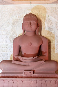 Isolated red stone jain god holy statue in meditation from different angle