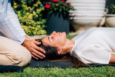 Woman in reiki spiritual healing session. reiki therapist holding hands above heart chakra 